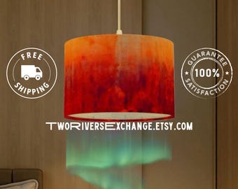 May include: A cylindrical pendant lamp with a gradient design, transitioning from orange to deep red. The lamp hangs from a white cord, with the text "TWORIVERSEXCHANGE.ETSY.COM" at the bottom. The image also includes a "Free Shipping" and "100% Satisfaction Guarantee" badge.
