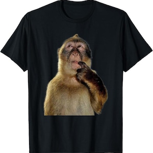 May include: Black t-shirt featuring a close-up image of a monkey with a thoughtful expression, its finger touching its lips. The monkey has brown and tan fur with a dark face. The shirt is a classic crew neck.