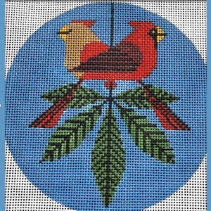 May include: A circular needlepoint canvas featuring a cross-stitched design of two birds, one yellow and one red, perched atop a cluster of five green leaves. The background is a solid blue grid pattern, and the entire piece is on white mesh.