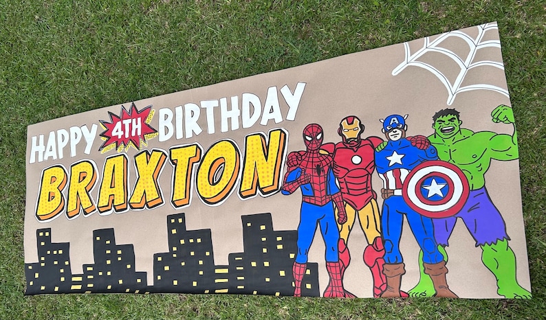 May include: A rectangular banner with a tan background featuring the text "HAPPY 4TH BIRTHDAY BRAXTON" in bold white and yellow letters. The design includes a black city skyline, a white spiderweb, and illustrations of Spider-Man, Iron Man, Captain America, and the Hulk.