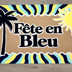 May include: A rectangular sign featuring a wavy, sunburst pattern in navy blue, light blue, and yellow. Centered is a tan, scalloped-edge rectangle with the text "F&ecirc;te en Bleu" in black, flanked by a black palm tree silhouette and a yellow sun.