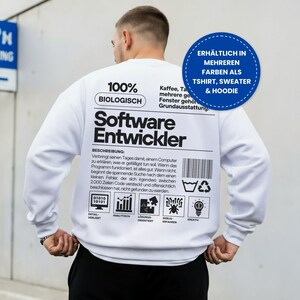 Könnte beinhalten: Ein weißes Langarm-Sweatshirt mit schwarzem Text und grafischen Symbolen auf der Rückseite. Das Design enthält die Wörter 100% BIOLOGISCH, Software Entwickler, einen beschreibenden Text, einen Barcode, ein Recyclingsymbol und fünf kleine Icons.