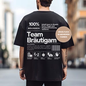 Puede incluir: Camiseta negra con texto y gr&aacute;ficos blancos. El texto incluye "100% BIOLOGISCH Team Br&auml;utigam" y varios iconos. Un gr&aacute;fico circular indica "DISPONIBLE EN M&Aacute;S COLORES". La camiseta es de estilo casual.