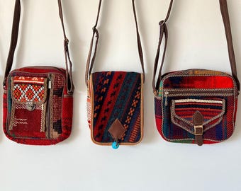 Pode incluir: Uma coleção de quatro bolsas tiracolo retangulares em tecido trançado com padrões geométricos multicoloridos em tons de vermelho, azul e marrom. Cada bolsa inclui uma alça de ombro marrom longa, bolsos frontais e fechos de metal.