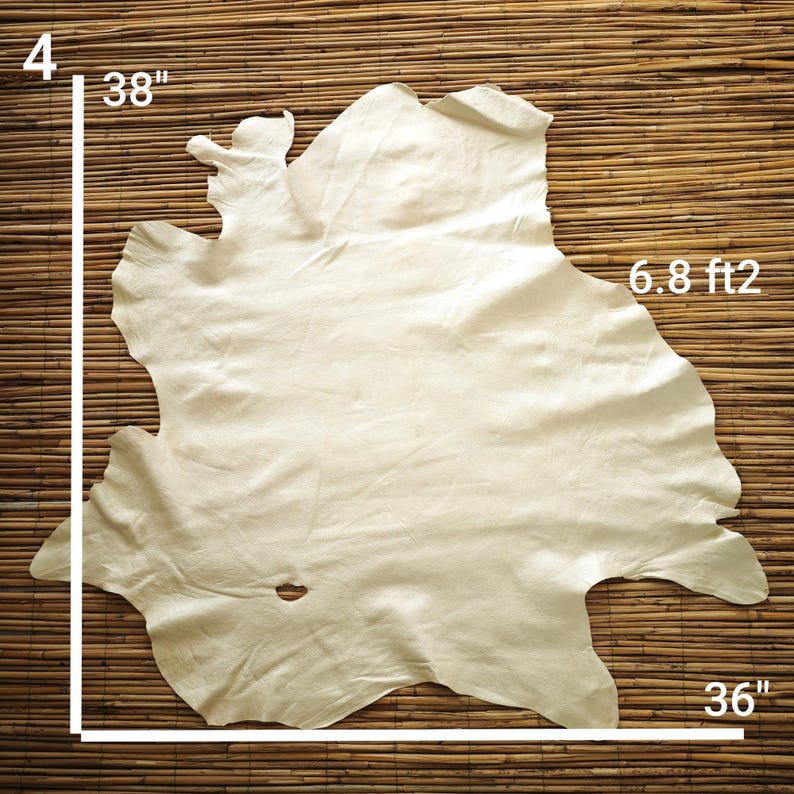 May include: A cream-colored leather hide, approximately 38 inches by 36 inches, with a surface area of 6.8 square feet. The hide has irregular edges and a natural, organic shape. The background is a woven bamboo mat.