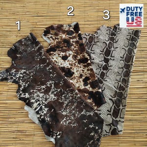 May include: Three pieces of leather with different patterns. The first is dark brown with white splatters. The second is brown and white spotted. The third is a snakeskin pattern in brown and cream. The background is a bamboo mat.