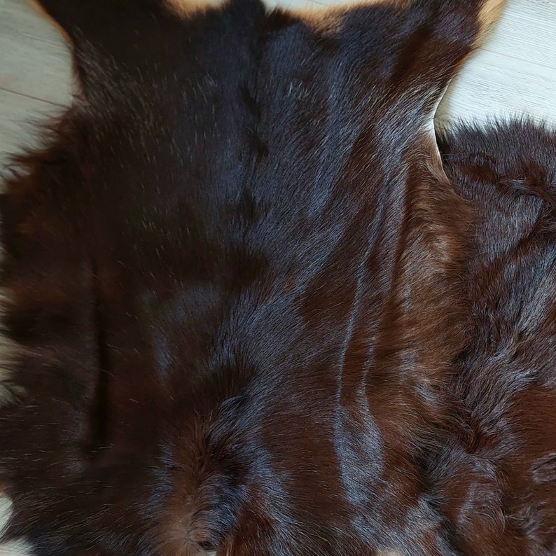 May include: A close-up of a brown cowhide rug with a soft, fuzzy texture.