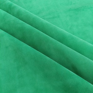 May include: A close-up of a smooth, green fabric with soft folds. The fabric has a subtle texture and a rich, vibrant color.