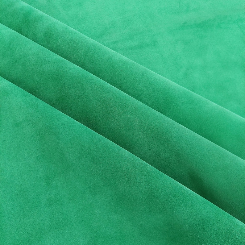 May include: A close-up of a smooth, green fabric with soft folds. The fabric has a subtle texture and a rich, vibrant color.