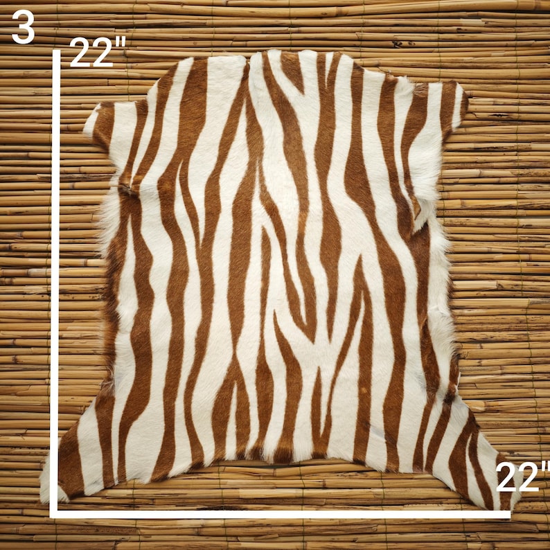 May include: A zebra-striped hide rug, measuring 22 inches wide and 22 inches long, with a brown and white pattern. The rug is displayed on a bamboo mat background.