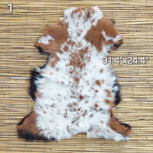 May include: A cowhide rug with a natural pattern of brown, white, and black. The rug measures 31.4 inches by 24.4 inches. The hide has a soft, textured appearance and is displayed on a bamboo mat.