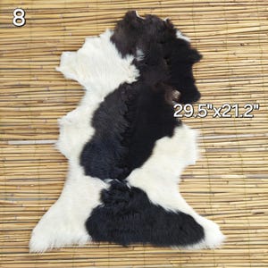 May include: A cowhide rug with a distinctive black and white pattern. The rug measures 29.5" x 21.2" and features a mix of long and short fur. The number "8" is in the upper left corner.