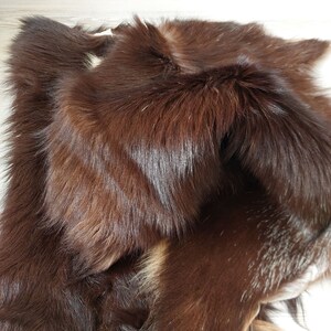 May include: A brown fur pelt with a soft, fluffy texture. The fur is folded over itself, revealing the underside of the pelt.