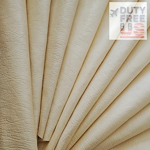 May include: A fan of cream-colored leather sheets, with a textured surface. The sheets are arranged to display their layered structure. The image includes the text "DUTY FREE US".