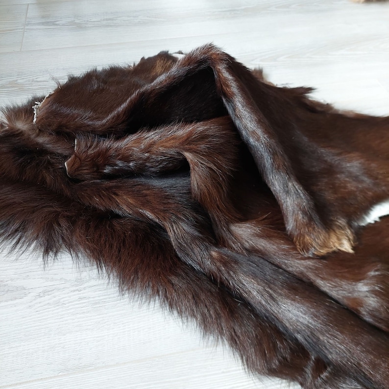 May include: A brown fur pelt with long, soft fur. The fur is folded in half, showing the underside of the pelt.