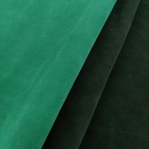 May include: Two pieces of fabric, one dark green and one black, are folded over each other. The fabric has a soft, velvety texture.