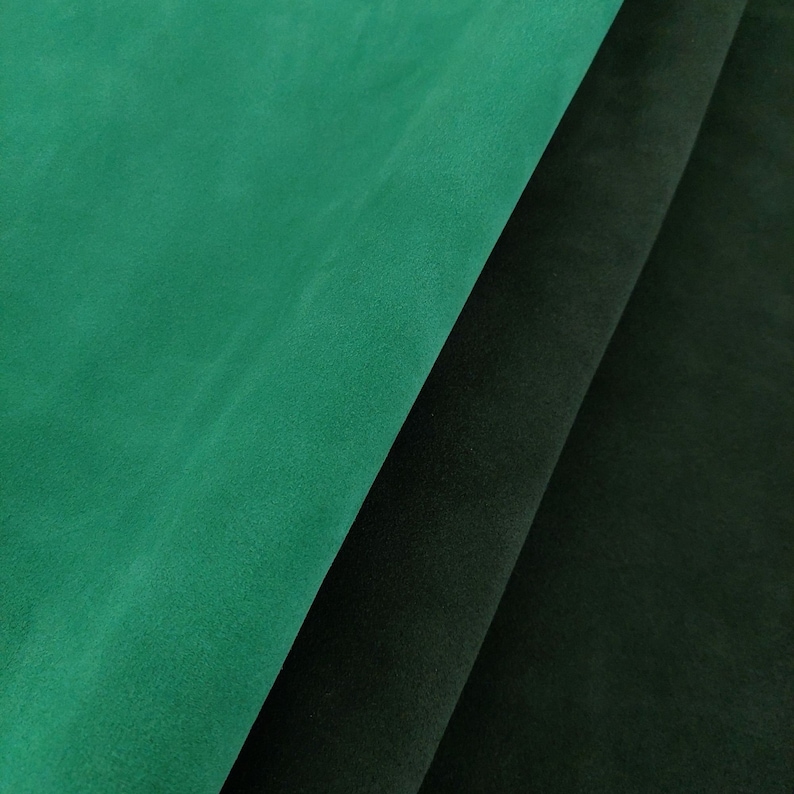 May include: Two pieces of fabric, one dark green and one black, are folded over each other. The fabric has a soft, velvety texture.