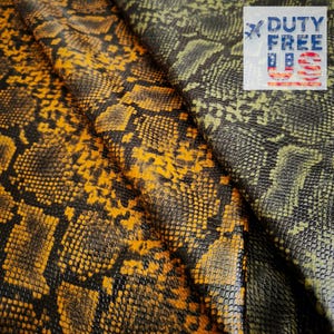 Può includere: Primo piano di due pezzi di ecopelle con motivo a pelle di serpente. Un pezzo è principalmente giallo e nero, l'altro verde e nero. Il logo Duty Free US si trova nell'angolo in alto a destra.