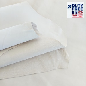 May include: Close-up of several sheets of white leather, some rolled and layered. The leather has a smooth, soft texture. The image includes the text "DUTY FREE US" in the upper right corner.