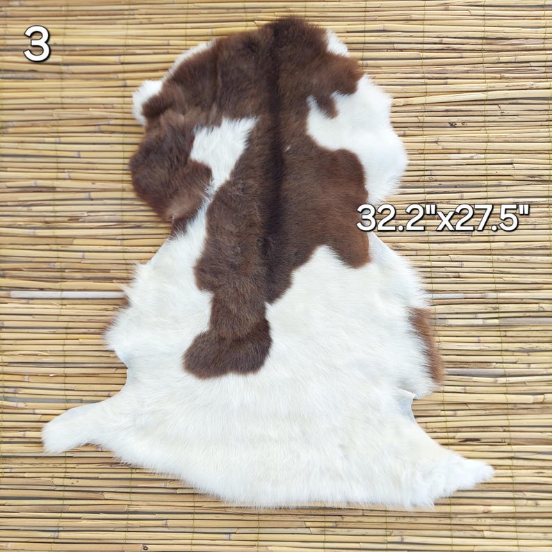 May include: A cowhide rug with a brown and white pattern. The rug measures 32.2 inches by 27.5 inches. The number "3" is visible in the upper left corner. The rug is placed on a bamboo mat.