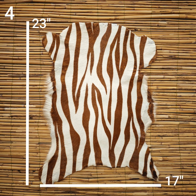 May include: A zebra-striped rug with brown and white patterns. The rug measures 23 inches long and 17 inches wide, with a 4-inch edge. The rug is made of a soft material and is suitable for home decor.