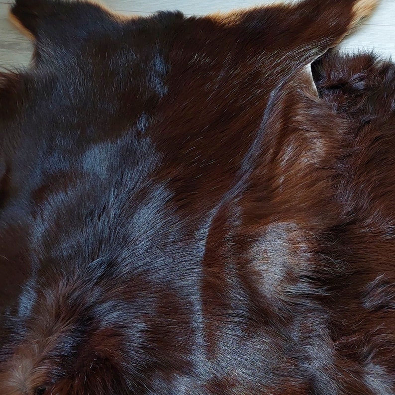 May include: A close-up of a brown cowhide rug with a soft, fuzzy texture.