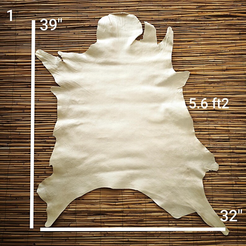 May include: A cream-colored leather hide, approximately 39 inches by 32 inches, with a surface area of 5.6 square feet. The hide has irregular edges and a natural texture, displayed against a bamboo background.