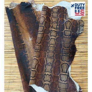 May include: Two pieces of brown and black reptile-patterned leather with a scale-like design. The leather has a textured surface. The image includes a "DUTY FREE US" logo.