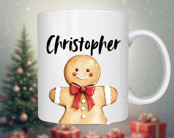 May include: White ceramic mug featuring a gingerbread man design with a red bow tie and the name "Christopher" in black script. The mug has a handle and is decorated with a festive Christmas theme.