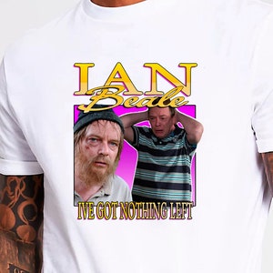 Pode incluir: Camiseta branca com um design gráfico. O design mostra o nome "IAN Beale" em amarelo sobre um fundo rosa, juntamente com duas imagens de um homem e o texto "I'VE GOT NOTHING LEFT".