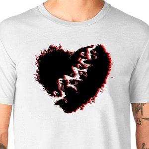 May include: White t-shirt with a black heart graphic. The heart is ripped and stitched with red thread.