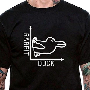 Może przedstawiać: Czarny t-shirt z białym nadrukiem przedstawiającym kaczkę narysowaną na wykresie. Oś x jest oznaczona jako "DUCK", a oś y jako "RABBIT".