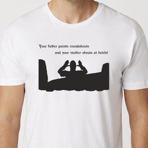 May include: White t-shirt with black text and graphic. The text reads "Your father paints roundabouts and your mother shouts at hotels!" A black silhouette of a person in a boat is below the text.