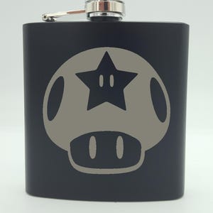 May include: Black metal flask with a silver cap and a gray star-shaped mushroom graphic.