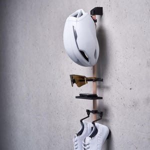 May include: White bicycle helmet, sunglasses, and white athletic shoes hanging on a wooden rack with black metal hooks.