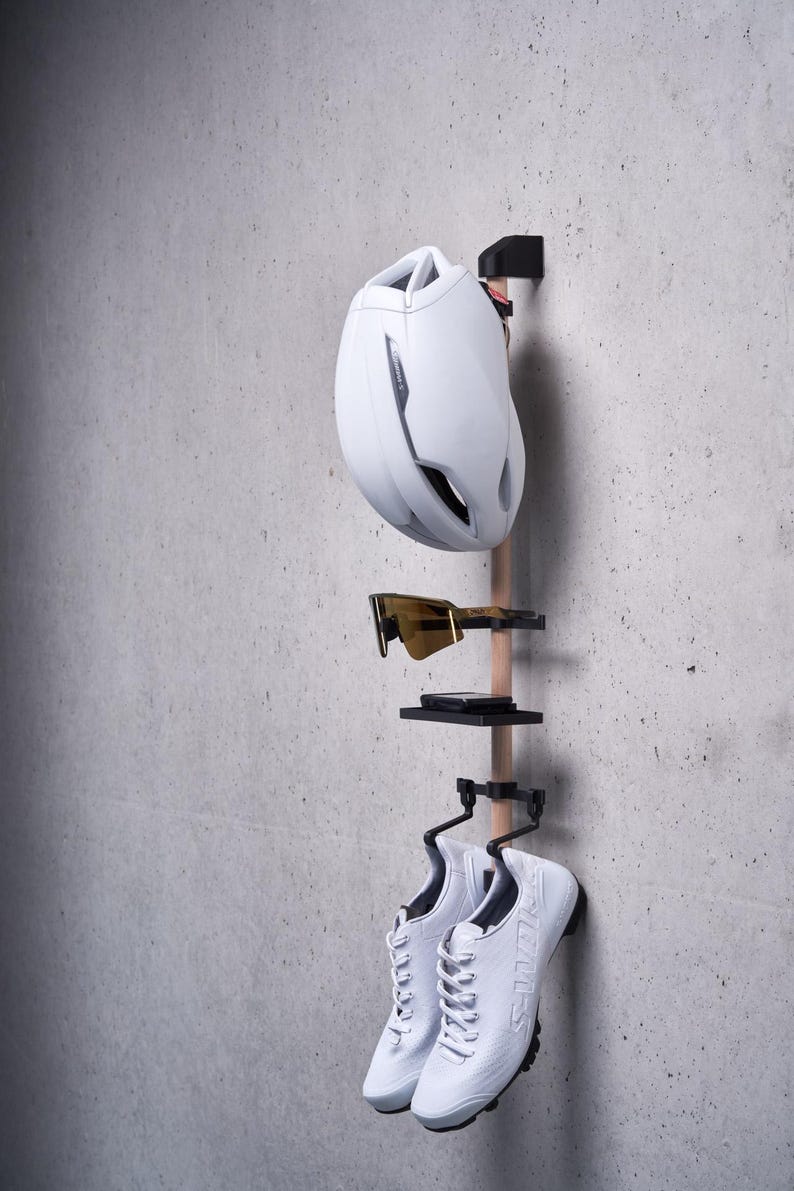May include: White bicycle helmet, sunglasses, and white athletic shoes hanging on a wooden rack with black metal hooks.
