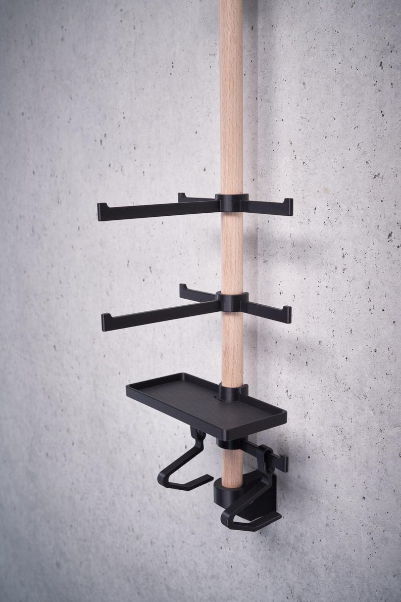 May include: A wooden pole with black metal shelves and hooks. The shelves are adjustable and can be moved up or down the pole. The hooks are also adjustable and can be moved to different positions on the shelves.