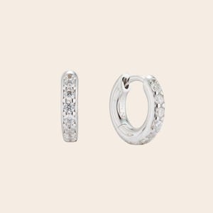 Small silver huggie hoops bathed in rhodium with prong-set zirconia stones. Minimalist stacking NANA earrings developed by Maison Noora