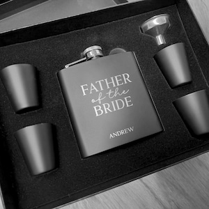 Może przedstawiać: Czarne pudełko prezentowe z czarną karafką grawerowaną napisem "Father of the Bride" i imieniem "Andrew". Pudełko zawiera również dwa kieliszki do shotów i lejek.