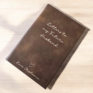 May include: A brown leather-bound journal with the words "Letters to my Future Husband" and "Love, Stephanie" inscribed on the front cover.