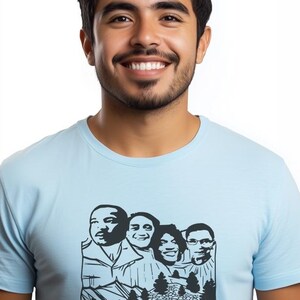 Puede incluir: Un hombre con una camiseta azul claro con un gráfico en blanco y negro de cuatro caras de personas. El gráfico recuerda al Monte Rushmore.