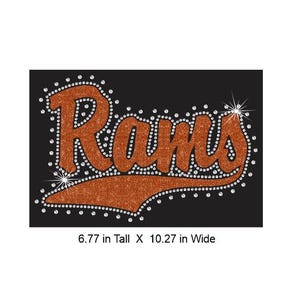 May include: A glittery orange iron-on transfer featuring the word Rams in a script font with a swoosh underline, outlined and accented with clear rhinestones on a black background, measuring 17.2 cm tall by 26.1 cm wide.