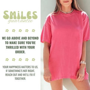May include: A vibrant pink t-shirt with short sleeves. The shirt is paired with a white background that includes text in green and white, including the words "SMILES guarantee" and "WE GO ABOVE AND BEYOND TO MAKE SURE YOU'RE THRILLED WITH YOUR ORDER."