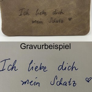 May include: A close-up of a brown leather item with the engraved text "Ich liebe dich mein Schatz" and a heart symbol. The text is in a handwritten style. Below, the text "Gravurbeispiel" is displayed.
