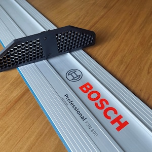 Może przedstawiać: Srebrna i niebieska szyna prowadząca Bosch Professional FSN 800 z czarnym plastikowym prowadnikiem. Szyny prowadzące mają czerwone logo Bosch i napis "Professional FSN 800".