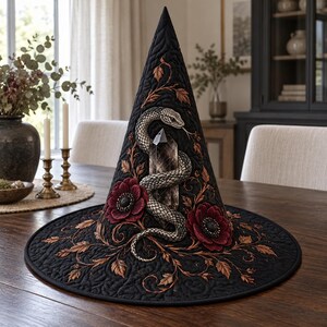 May include: A black quilted pointed hat featuring an embroidered silver snake coiled around a central dark crystal. The design includes deep red floral accents and copper-coloured vine embroidery that extends across the brim and cone.