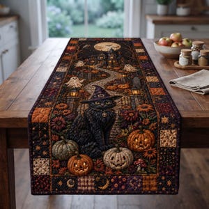 Puede incluir: Un camino de mesa acolchado rectangular con una escena de Halloween que muestra un gato negro con un sombrero de bruja morado, rodeado de calabazas, flores de otoño y fantasmas frente a una casa encantada bajo la luna llena.