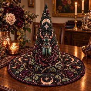 May include: A conical hat featuring a dark green quilted fabric base with an embroidered metallic beetle wearing a crown, surrounded by deep purple roses, golden star motifs, and crescent moon symbols. The wide brim is decorated with floral patterns.