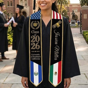 May include: A graduate in a black gown and mortarboard smiles, wearing a sash with "Class of 2026" and "University of Southern California." The sash displays the American flag, a scroll, and the name "Jessica Miller."