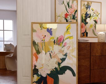 May include: Abstract floral art prints in wooden frames. The artwork features a bouquet of flowers in shades of white, pink, yellow, and green. The prints are displayed in a well-lit room with wooden floors and furniture.